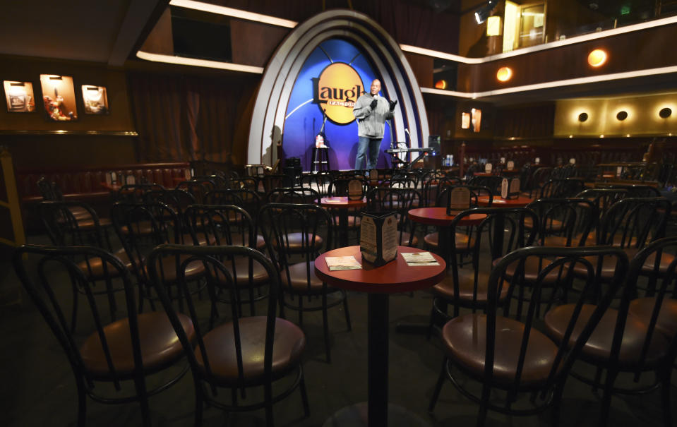 In this April 20, 2020, photo, empty chairs face comedian Alonzo Bodden as he performs during a "Laughter is Healing" stand-up comedy livestream event at the Laugh Factory in Los Angeles. With comedy clubs closed and concert tours put on hold, comics like Craig Robinson, Tiffany Haddish, Will C and others are keeping the jokes flowing on webcasts and Zoom calls even without the promise of a payday, because they say the laughs are needed now more than ever. (AP Photo/Chris Pizzello)