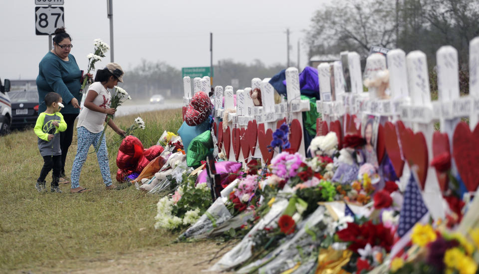 FILE - Christina Osborn and her children Alexander Osborn and Bella Araiza visit a makeshift memorial for the victims of the shooting at Sutherland Springs Baptist Church, Nov. 12, 2017, in Sutherland Springs, Texas. The Justice Department said Wednesday, April 5, 2023, that it has tentatively settled a lawsuit over the 2017 mass shooting at a Texas church that will pay victims and their families more than $144 million. (AP Photo/Eric Gay, File)