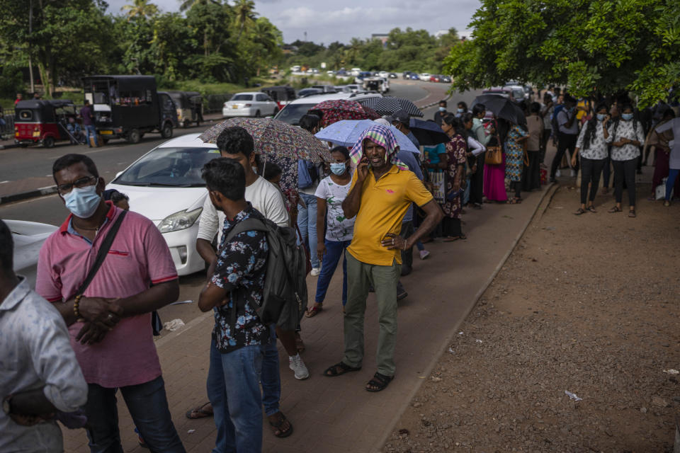 People wait in queue to get their passports outside Department of Immigration & Emigration in Colombo, Sri Lanka, Monday, July 18, 2022. The Indian Ocean island nation is engulfed in an unprecedented economic crisis that has triggered political uncertainty. (AP Photo/Rafiq Maqbool)