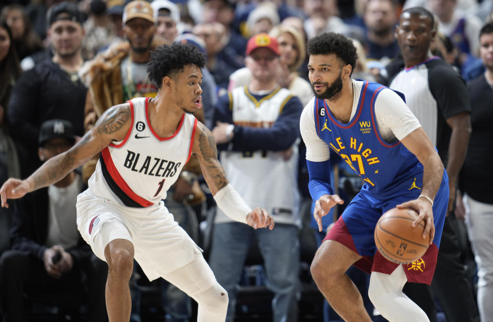 Denver Nuggets guard Jamal Murray, right, looks to pass the ball as Portland Trail Blazers guard Anfernee Simons defends in the first half of an NBA basketball game Friday, Dec. 23, 2022, in Denver. (AP Photo/David Zalubowski)