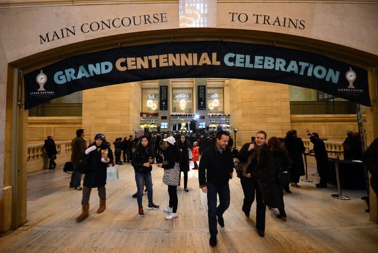 People walk under a banner set up as part of the centennial celebrations for Grand Central Terminal in New York, February 1 , 2013. Grand Central Terminal, the doyenne of US train stations, is celebrating its 100th birthday on February 2, 2013