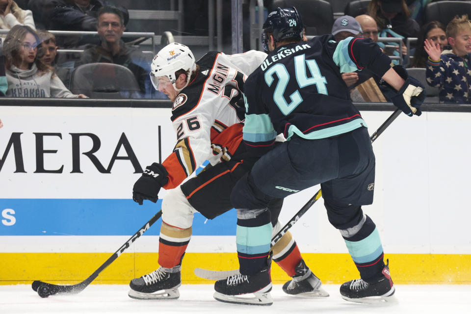 Anaheim Ducks left wing Brock McGinn (26) moves the puck while under pressure from Seattle Kraken defenseman Jamie Oleksiak (24) during the second period of an NHL hockey game Thursday, March 30, 2023, in Seattle. (AP Photo/Jason Redmond)