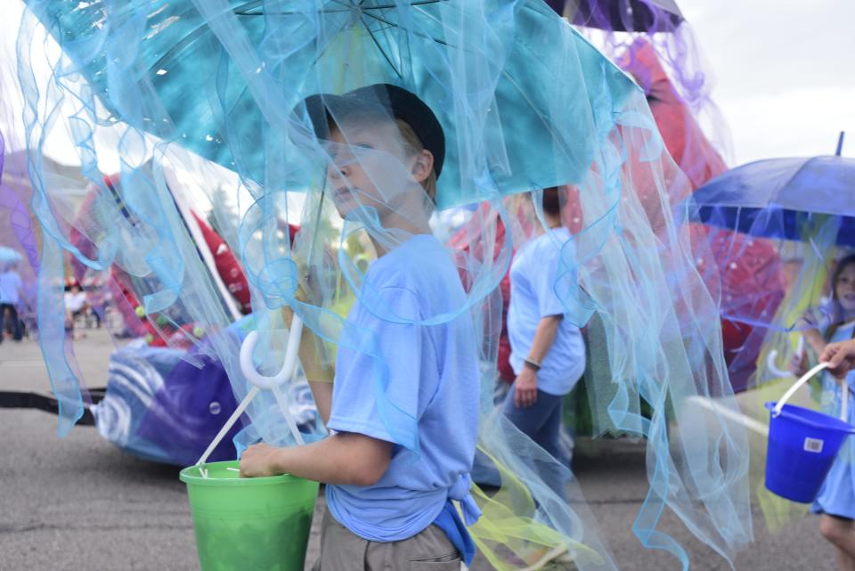 A parade volunteer marches down Huron Avenue holding a decorated umbrella during the annual Rotary International Day Parade to kick off Port Huron's Boat Week on Wednesday, July 13, 2022.