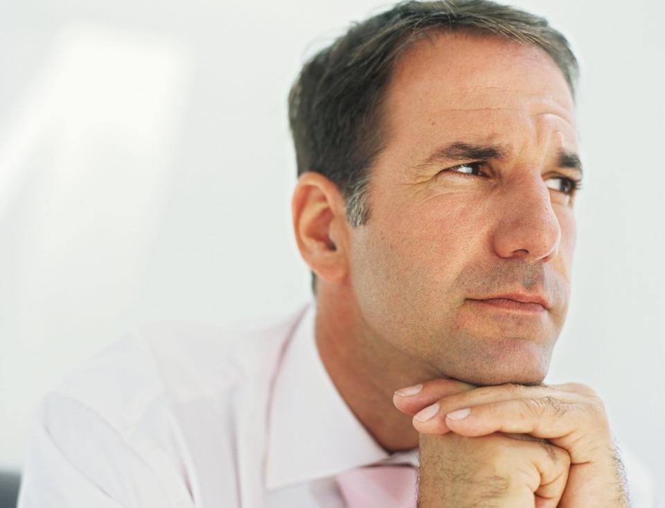 A person with their hands folded under their chin and looking deep in thought.