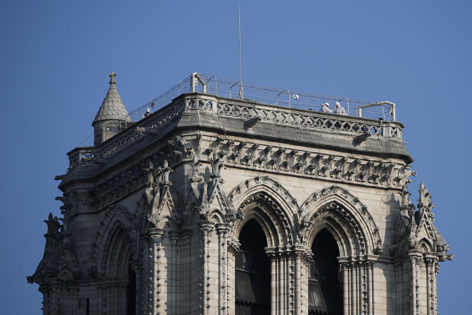 Workers stand atop a tower of Notre Dame cathedral, Thursday, April 15, 2021 in Paris. Two years after a fire tore through Paris' most famous cathedral and shocked the world, French President Emmanuel Macron is visiting the building site that Notre Dame has become to show that French heritage has not been forgotten despite the coronavirus. (AP Photo/Francois Mori)