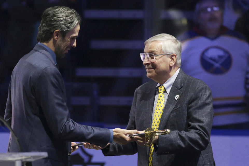 Former Buffalo Sabres goaltender Ryan Miller accepts a saber from Terry Pegula, owner of Pegula Sports and Entertainment, as Miller was honored before the Sabres' NHL hockey game against the New York Islanders on Thursday, Jan. 19, 2023, in Buffalo, N.Y. (AP Photo/Joshua Bessex)