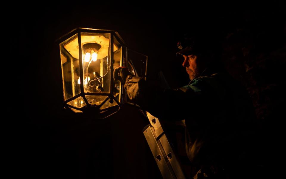 A lamp lighter winds the clock of the oldest gas lamp in England, at Westminster Abbey