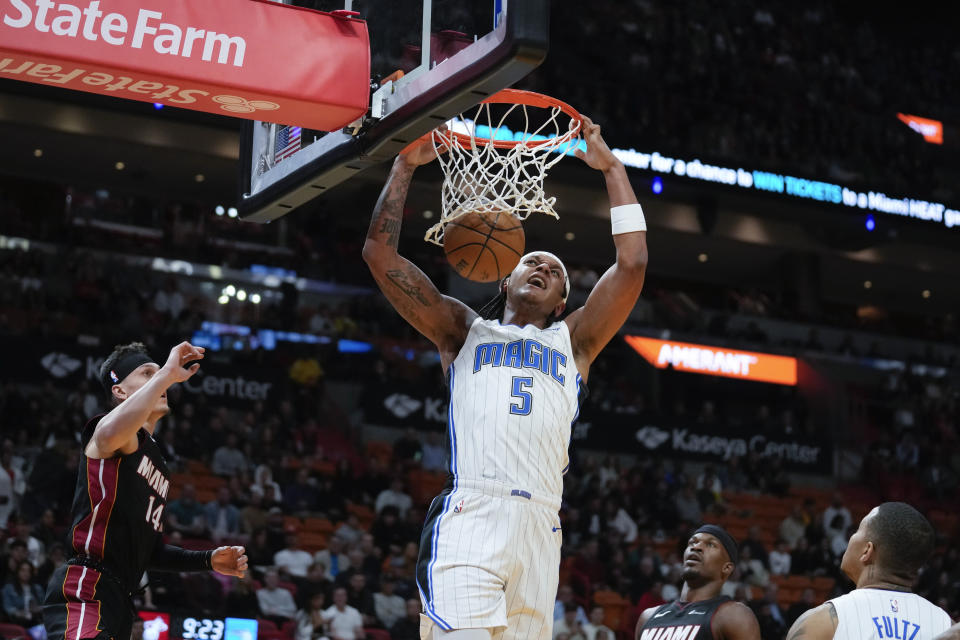 Orlando Magic forward Paolo Banchero (5) dunks as Miami Heat guard Tyler Herro (14) and Miami Heat forward Jimmy Butler look on during the first half of an NBA basketball game, Tuesday, Feb. 6, 2024, in Miami. (AP Photo/Rebecca Blackwell)