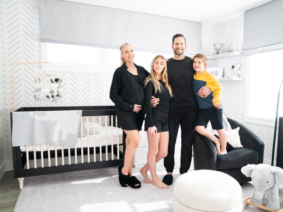 Tarek and Heather Rae El Moussa stand in a nursery with their children.