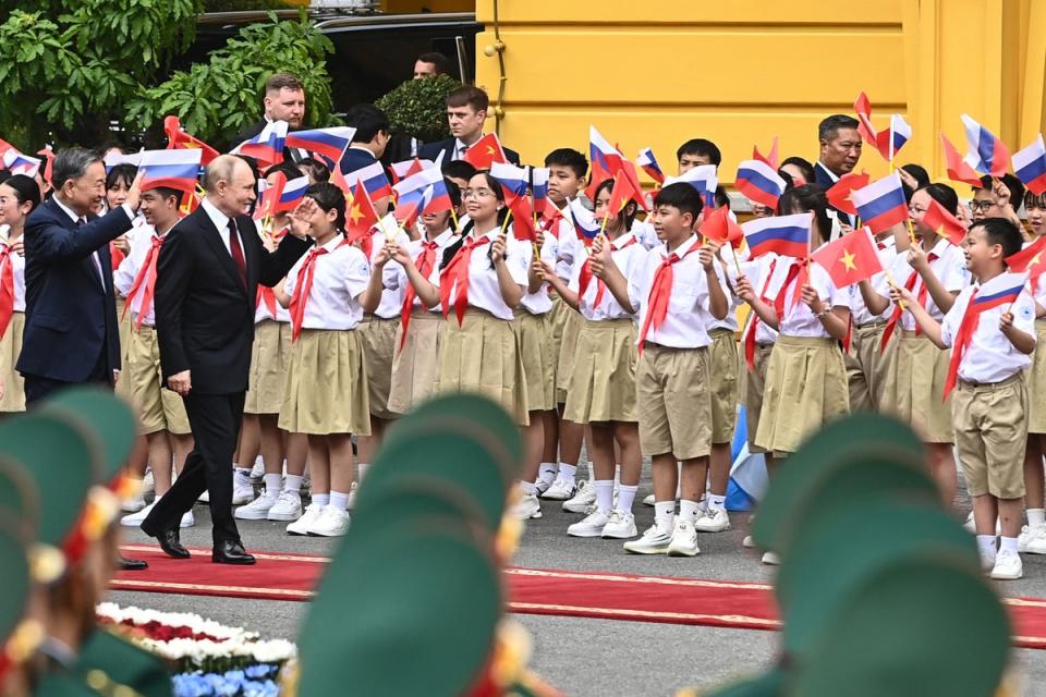 Russia's President Vladimir Putin and Vietnam's President To Lam (L) wave to children  holding Vietnamese and Russian flags during a welcome ceremony (AFP via Getty Images)