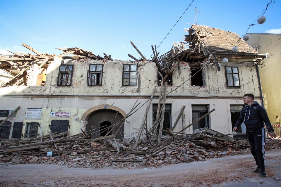 A man walks next to rubble and damaged buildings in Petrinja, some 50kms from Zagreb, after the town was hit by an earthquake of the magnitude of 6,4 on December 29, 2020. - The tremor, one of the strongest to rock Croatia in recent years, collapsed rooftops in Petrinja, home to some 20,000 people, and left the streets strewn with bricks and other debris. Rescue workers and the army were deployed to search for trapped residents, as a girl was reported dead. (Photo by Damir SENCAR / AFP) (Photo by DAMIR SENCAR/AFP via Getty Images)