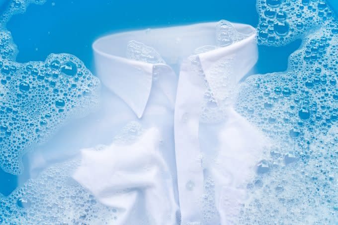 close up of a white shirt soaking in sudsy water for laundry pre-treatment