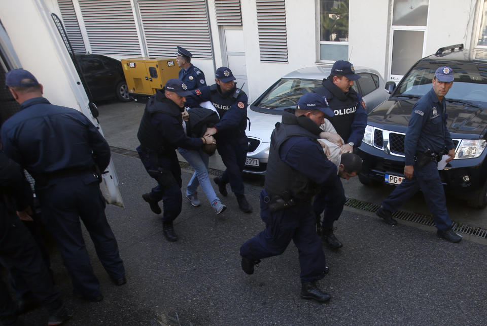 FILE - In this Sunday, Oct. 16, 2016 file photo, Montenegrin police officers escort people suspected of planning armed attacks after the parliamentary vote in Podgorica, Montenegro. A court in Montenegro has sentenced 13 people, including two Russian secret service operatives, to up to 15 years in prison after they were found guilty of plotting to overthrow the Balkan country's government and prevent it from joining NATO. (AP Photo/Darko Vojinovic, File)