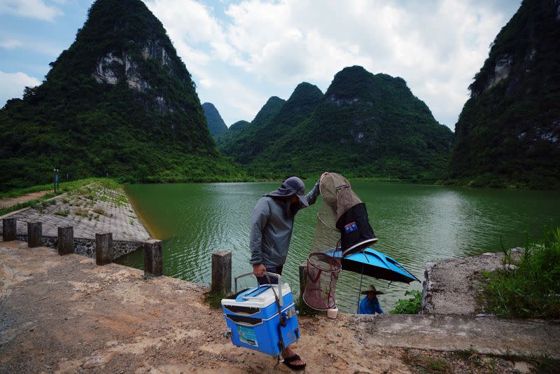 FILE PHOTO: Man walks past the Longcheng reservoir with fishing equipment in Yangshuo