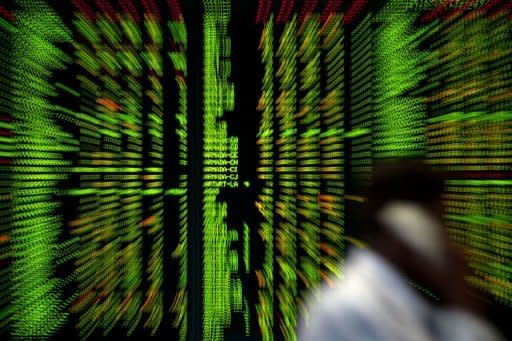 A Malaysian trader talks on a phone in front of a digital share prices board in Kuala Lumpur. World stock markets mostly fell on Friday after the economic outlook in Germany soured sharply, with bank shares in focus after Moody's downgraded some of the biggest names including HSBC