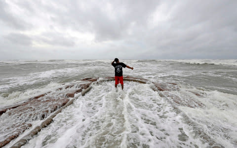 Luis Perez watches waves crash again a jetty in Galveston, Texas as Hurricane Harvey intensifies in the Gulf of Mexico Friday, Aug. 25, 2017 - Credit: AP