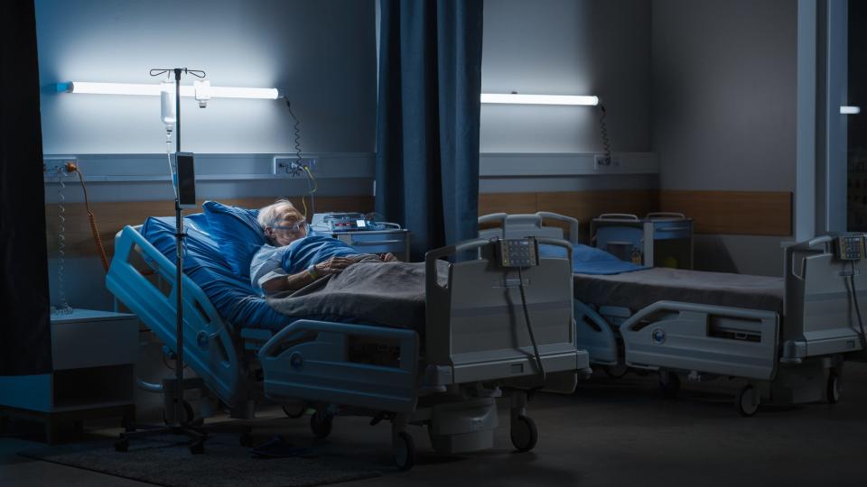 Hospital Ward: Portrait of Elderly Man Wearing Oxygen Mask Resting in Bed, Struggling to Recover after Covid-19