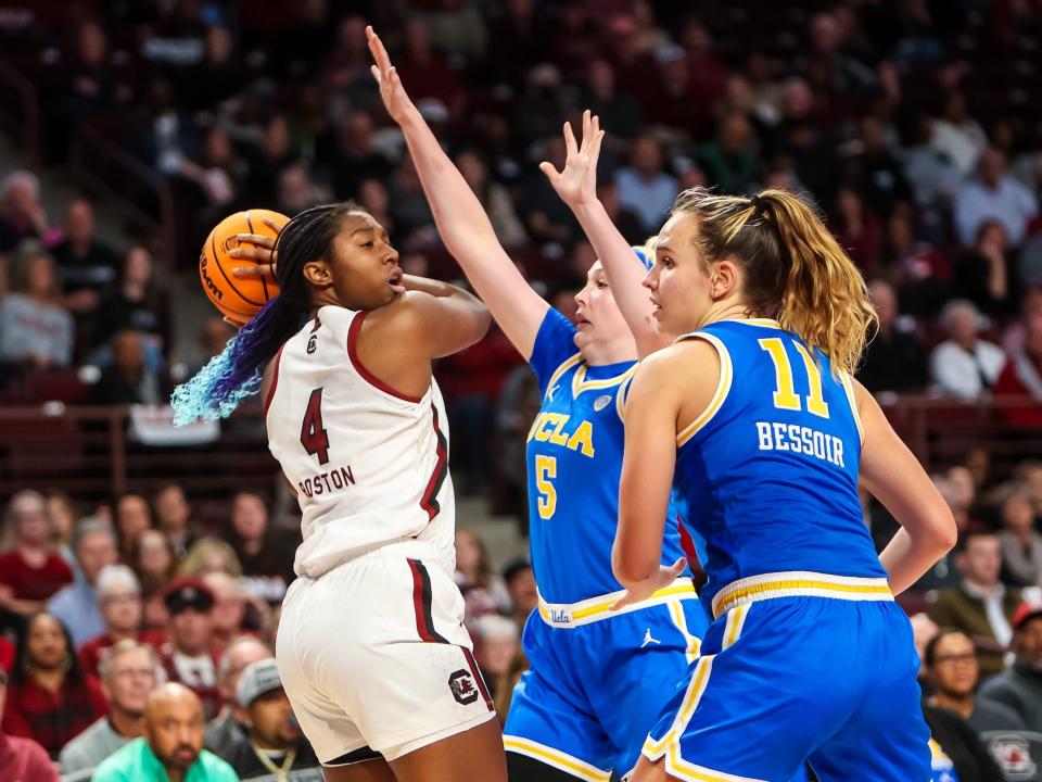 Aliyah Boston looks to move the ball around two UCLA Bruins defenders.