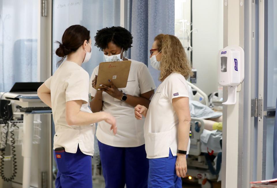 Vanessa Jean-Baptiste, center, a registered nurse in the intensive care unit at Northern Westchester Hospital in Mount Kisco, goes over patient information with fellow nurse Annmarie Tietjen and nurse manager Laura Burke on March 1, 2022, at the end of Jean-Baptiste's 12-hour shift.