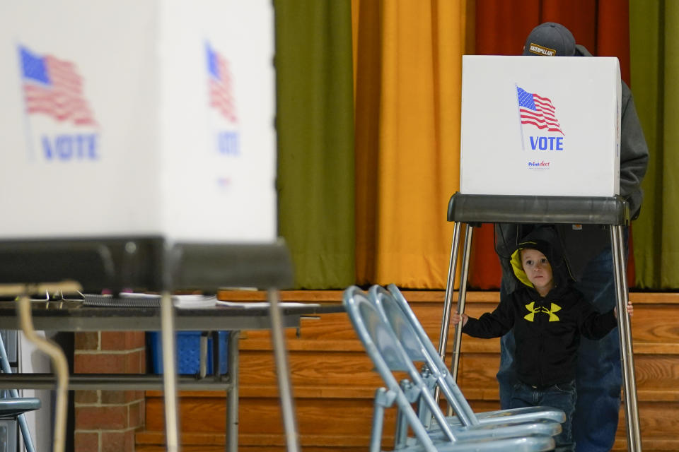 Jacob Lewis, 3, waits at a privacy booth as his grandfather, Robert Schroyer, fills out his ballot while voting at Sabillasville Elementary School, Tuesday, Nov. 8, 2022, in Sabillasville, Md. (AP Photo/Julio Cortez)