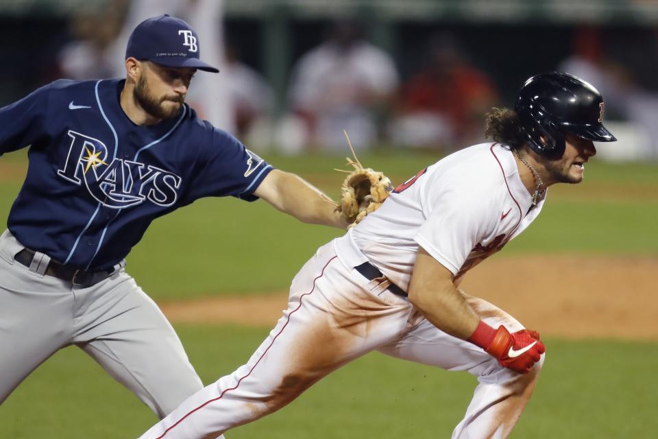 Tampa Bay Rays' Brandon Lowe tags Boston Red Sox's Andrew Benintendi on a run down at third base during the eighth inning of a baseball game, Tuesday, Aug. 11, 2020, in Boston. (AP Photo/Michael Dwyer)