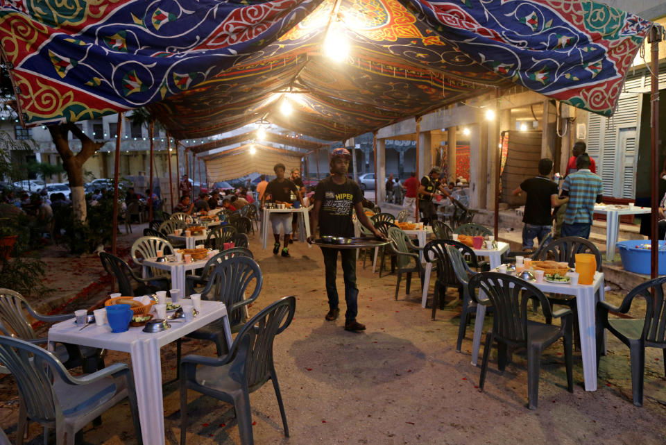 A volunteer carries food to tables set up by a charity as people wait to eat their Iftar (breaking of fast) meal during the holy fasting month of Ramadan in Benghazi, Libya June  20, 2017. REUTERS/Esam Omran Al-Fetori