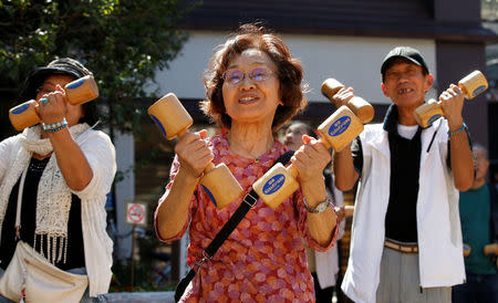 Elderly and middle-aged people exercise with wooden dumbbells during a health promotion event to mark Japan's "Respect for the Aged Day" at a temple in Tokyo's Sugamo district, an area popular among the Japanese elderly, Japan, September 18, 2017. REUTERS/Toru Hanai