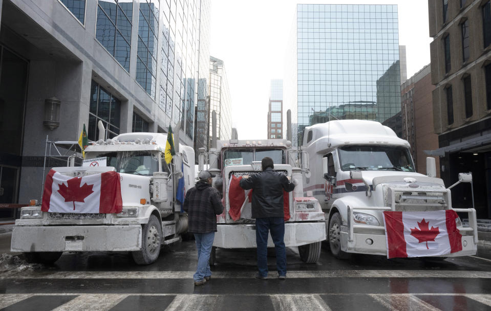 FILE - Truck drivers hang a Canadian flag on the front grill of a truck parked in downtown Ottawa, Ontario, near Parliament Hill on Wednesday, Feb. 2, 2022. On Friday, Feb. 4, The Associated Press reported on stories circulating online incorrectly claiming law enforcement officials in Canada report over 100,000 trucks and millions of people showed up last weekend in Ottawa for a vaccine mandate protest. (Adrian Wyld/The Canadian Press via AP, File)