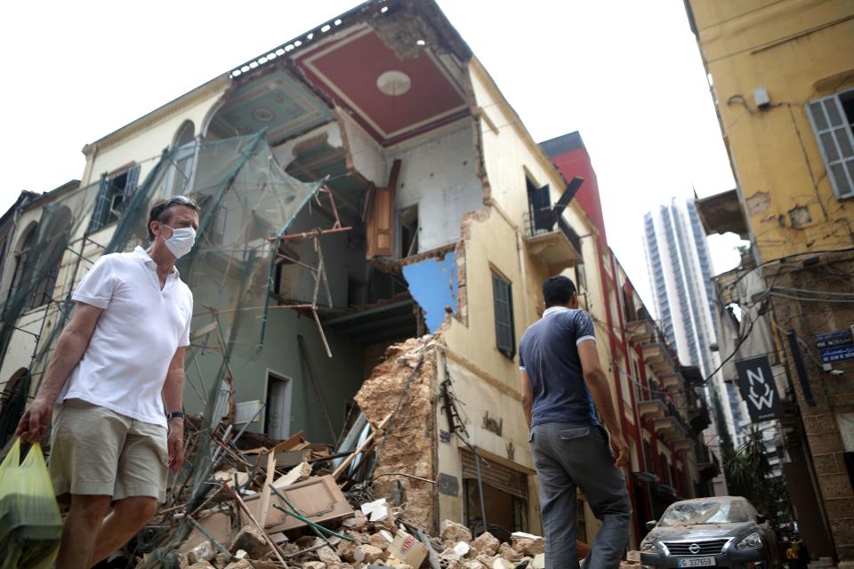 People walk past a destroyed building in Beirut on August 7, 2020. / Credit: PATRICK BAZ/AFP via Getty Images