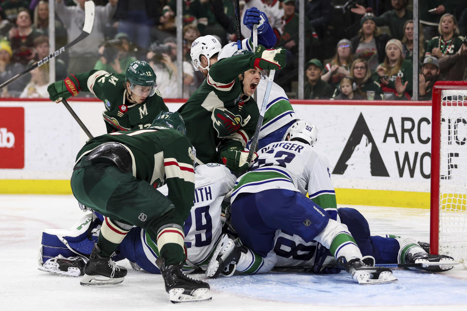 Minnesota Wild center Joel Eriksson Ek, middle, reacts as members of the Vancouver Canucks and Minnesota Wild compete for the puck in front of the net during the third period of an NHL hockey game, Monday, Feb. 19, 2024, in St. Paul, Minn. (AP Photo/Matt Krohn)