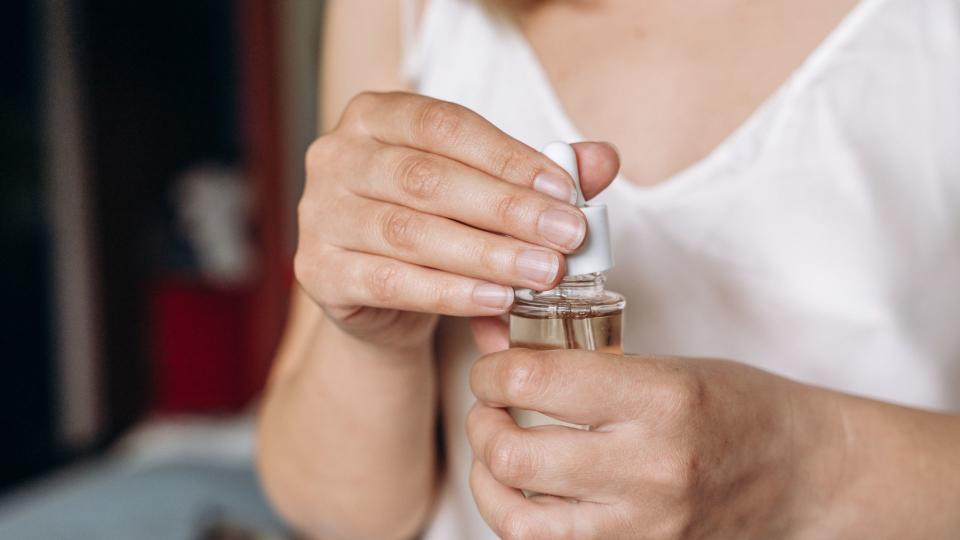 woman opening facial oil bottle