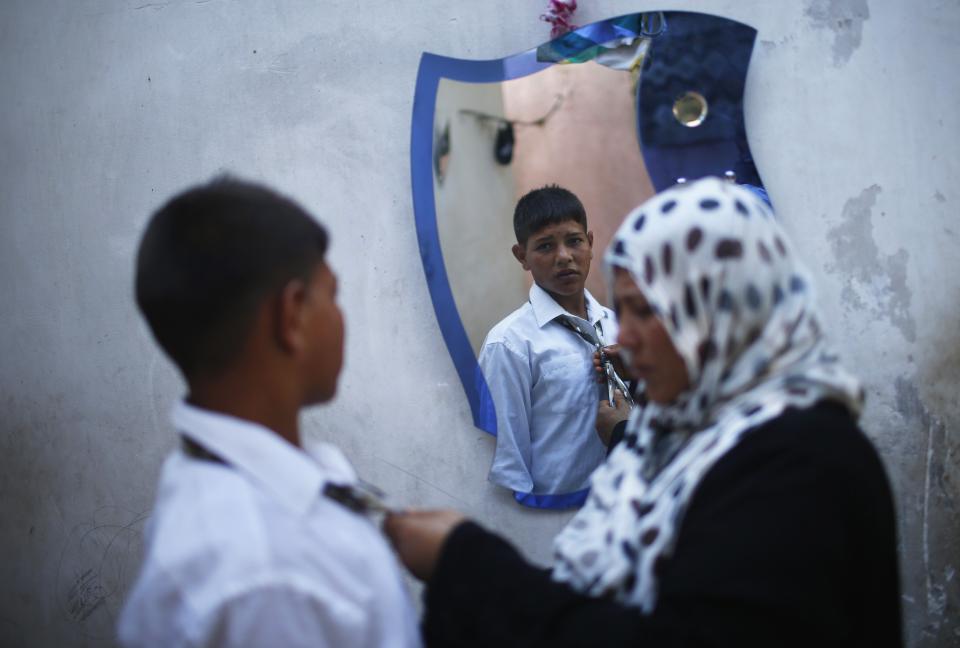 The mother of young Palestinian groom Soboh helps him prepare for wedding party with bride Tala in Beit Lahiya