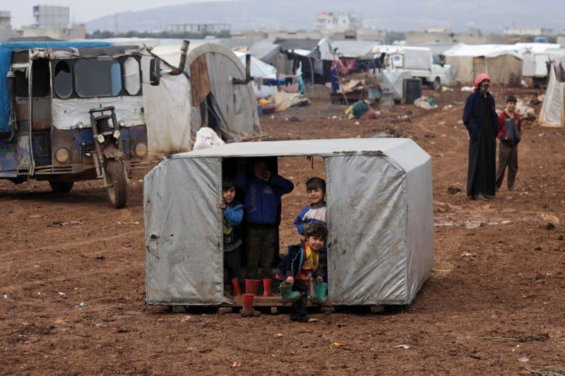 Internally displaced children look out from a tent at a makeshift camp in Azaz