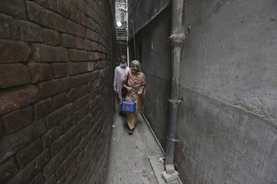 Health workers pass through an alley to give polio vaccines to children in a neighborhood of Lahore, Pakistan, Monday, May 23, 2022. Pakistan launched a new anti-polio drive on Monday, more than a week after officials detected the third case so far this year in the country's northwestern region bordering Afghanistan. (AP Photo/K.M. Chaudary)