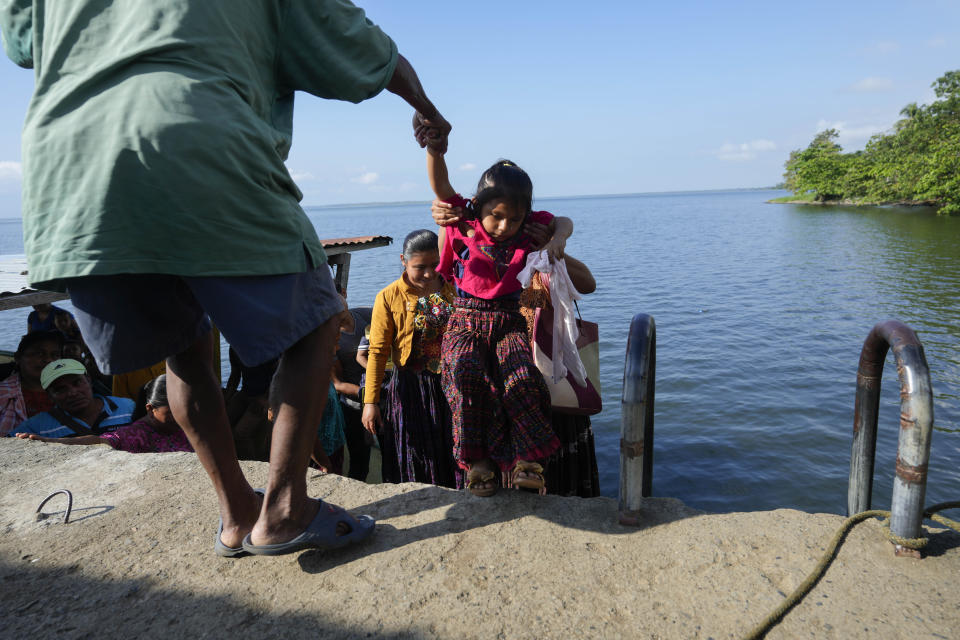 Residents from the nearby village of Pataxte arrive to El Estor, Guatemala, Monday, Oct. 25, 2021, during permitted hours of travel amid a curfew. The Guatemalan government has declared a month-long, dawn-to-dusk curfew and banned pubic gatherings following protests against a nickel mining project. (AP Photo/Moises Castillo)