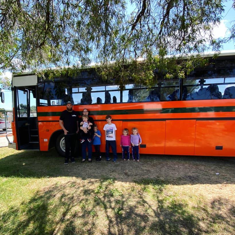 Jo and Gary Pascoe and their five children outside their bright orange school bus