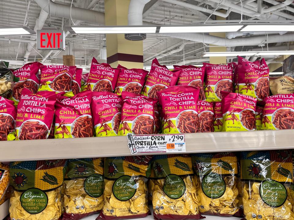 Pink and yellow bags of Trader Joe's chile-kime rolled-corn tortilla chips on top shelf