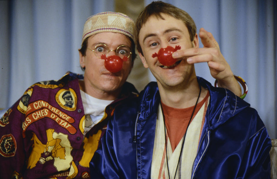 ENGLAND : Nicholas Lyndhurst and a guest show off the books sold for Red Nose Day 1991 in 1991 in England. (Photo by Mauro Carraro/Comic Relief via Getty Images)