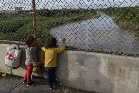 Honduran girls look out at the Rio Grande on the Mexican side of the Brownsville & Matamoros International Bridge after their asylum seeking families were denied entry by U.S. Customs and Border Protection officers near Brownsville, June 24. REUTERS/Loren Elliott