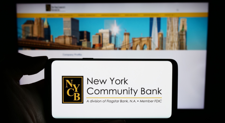 Person holding cellphone with logo of US company New York Community Bancorp Inc. (NYCB) in front of business webpage. Focus on phone display. Unmodified photo.