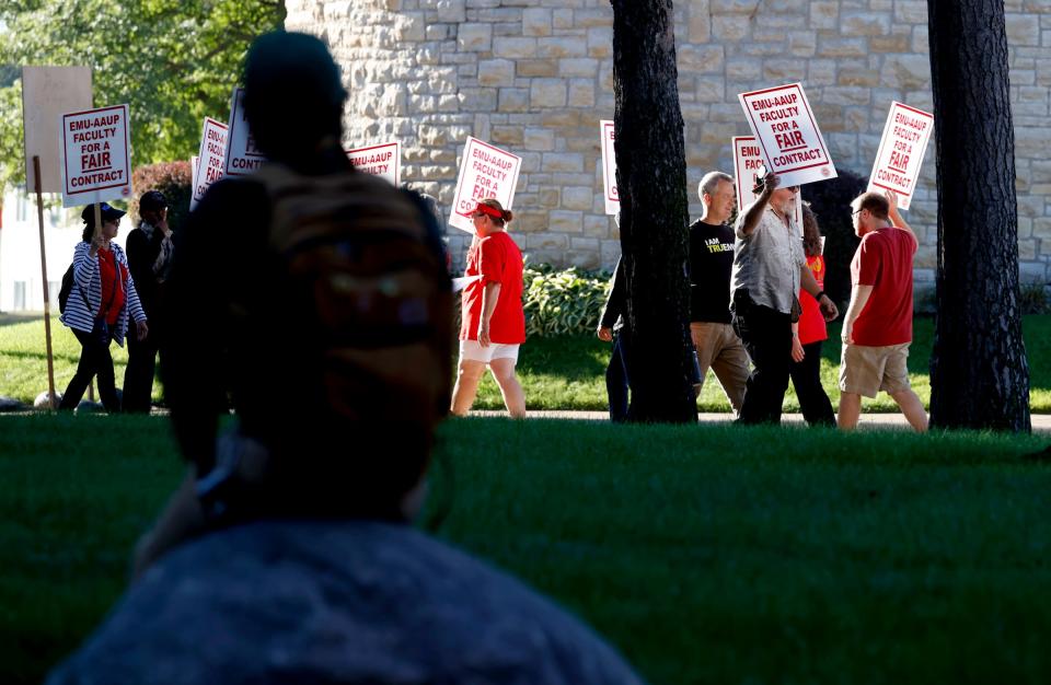 Hunter Allen, 18, of Howell, a freshman at Eastern Michigan University, sits on a rock watching faculty protest and strike in front of Welch Hall, the school's administration building on Wednesday, Sept. 7, 2022. The 500 professors that are part of the EMU American Association of University Professors voted on Tuesday night to strike for more pay and to not have their health care raised.