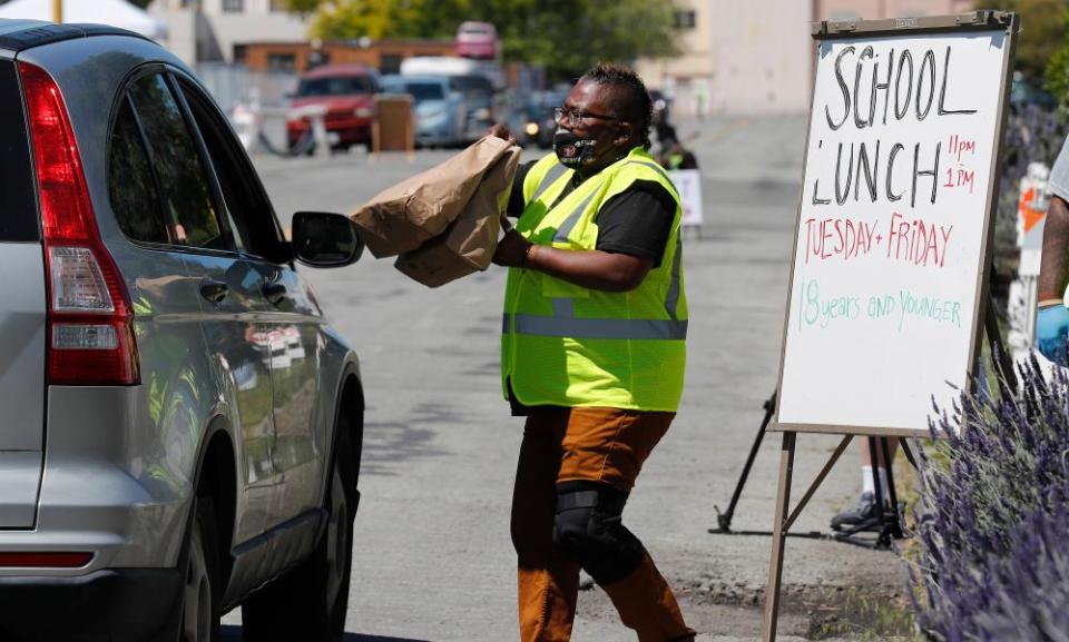 A volunteer delivers children school lunches to a car in Alameda, California in April 2020.