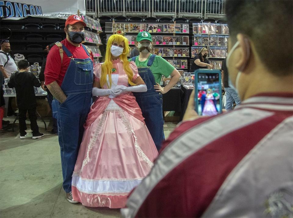 Keith Newsted of Stockton, left, his wife Korrie Newsted and her daughter Leo, dressed as Nintendo characters Mario, Princess Peach and Luigi, pose for a picture at the 2021 StocktonCon at the Stockton Arena in downtown Stockton. 