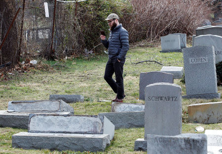 A visitor to the Mount Carmel Cemetery, a Jewish cemetery, makes a video recording of the headstones laying on the ground after vandals pushed them off their bases, in Philadelphia, Pennsylvania, U.S. February 27, 2017. REUTERS/Tom Mihalek