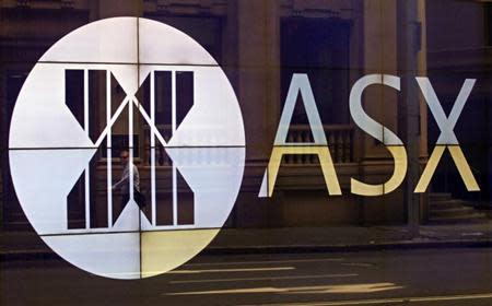 An office worker walks past the board of the Australian Securities Exchange building displaying its logo in central Sydney April 5, 2013. REUTERS/Daniel Munoz