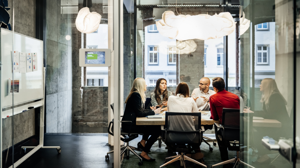 Young people sitting around a conference table in a modern office.