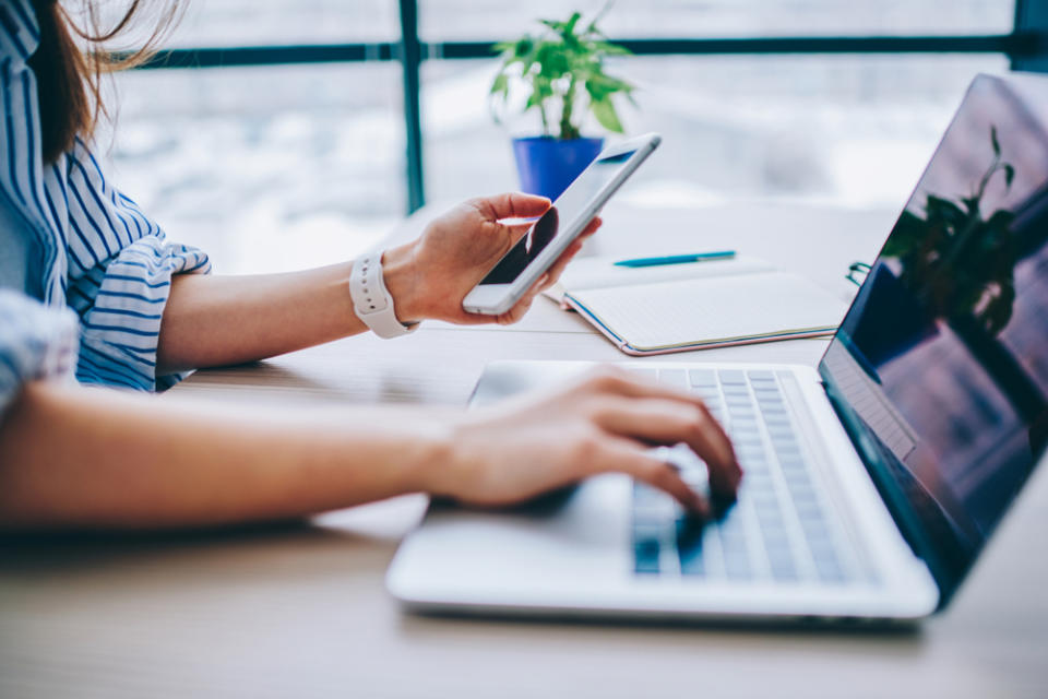 Woman using smartphone and laptop