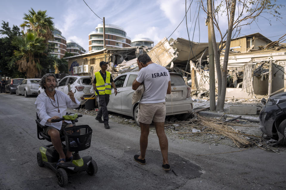 Israelis inspect the rubble of a building a day after it was hit by a rocket fired from the Gaza Strip, in Tel Aviv, Israel, Sunday, Oct. 8, 2023. The militant Hamas rulers of the Gaza Strip carried out an unprecedented, multi-front attack on Israel at daybreak Saturday, firing thousands of rockets as dozens of Hamas fighters infiltrated the heavily fortified border in several locations by air, land, and sea, killing hundreds and taking captives. Palestinian health officials reported scores of deaths from Israeli airstrikes in Gaza. (AP Photo/Oded Balilty)