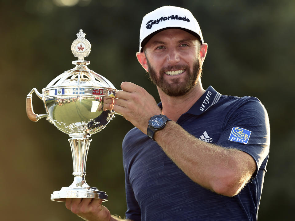 Dustin Johnson, of the United States, hoists the Canadian Open championship trophy at the Glen Abbey Golf Club in Oakville, Ontario, Sunday, July 29, 2018. (Nathan Denette/The Canadian Press via AP)