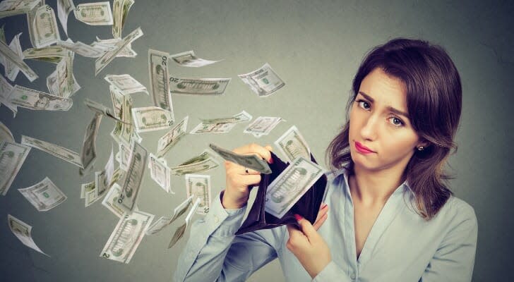 A woman watching as $20 bills float out of her billfold.